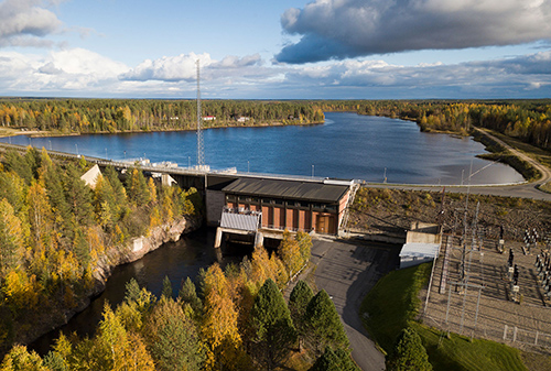 Vesivoimalaitos ja sen yläpuolinen järvi ilmasta kuvattuna syksyisessä maisemassa